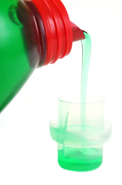 Pour liquid laundry into a plastic cap in close-up on white background