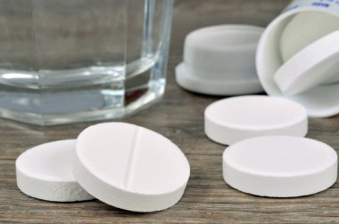 Aspirin tabletleri bir bardak suyun yanına kapanır. 