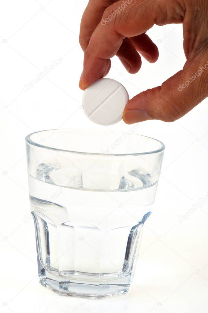 Put an aspirin tablet in a glass close up on white background 