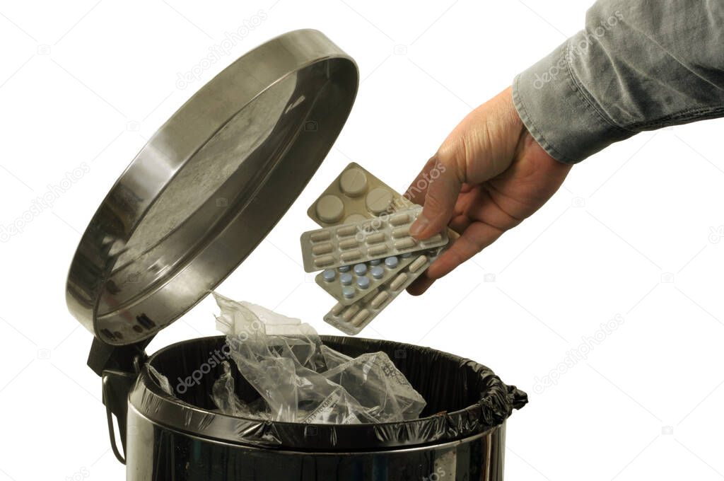 Man throwing expired medicines in the trash close up on white background