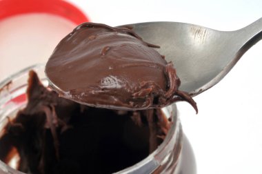 Kaşık ve kavanoz çikolata beyaz arka planda yakın çekim 