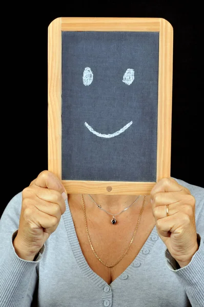 Woman hiding behind a school slate with a smiley face drawn