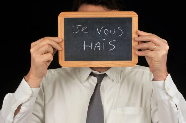一个无名小卒用一块写着法语的石板蒙着脸我讨厌你 — 图库照片