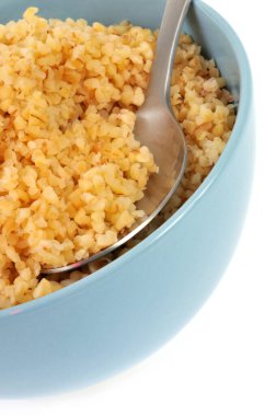 Beyaz arka planda kaşıkla yakın plan bulgur buğdayı kasesi