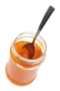 Kayısı reçeli kavanozu ve beyaz arka planda bir kaşık yakın plan