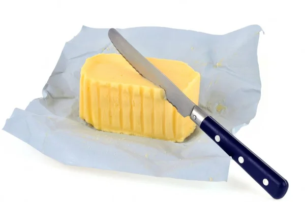 Stück Butter Packpapier Mit Messer Nahaufnahme Auf Weißem Hintergrund — Stockfoto