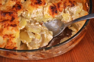 Bir tabak patatesli graten ve yakın plan kaşık.