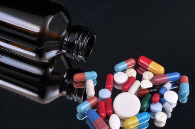 Siyah arka plana dökülen ilaç şişesi.