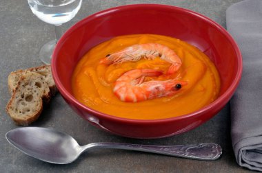 Bir tabak karides çorbası, kaşık ve tost. 