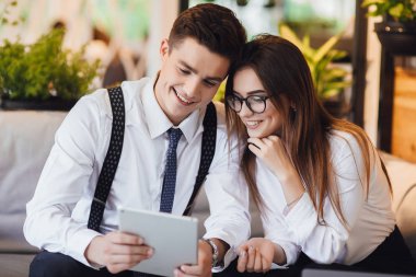 İki genç insan tablet ile kafede gün için plan tartışıyor