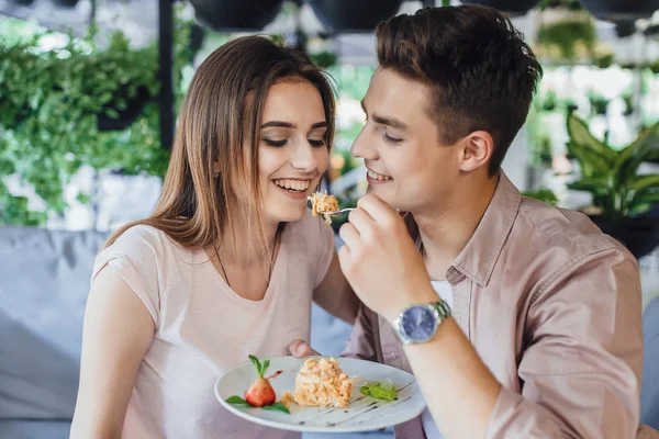 young handsome man feeding woman delicious cake