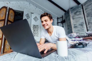 dizüstü bilgisayarda çalışarak freelancer konforlu evde yatakta yatarken