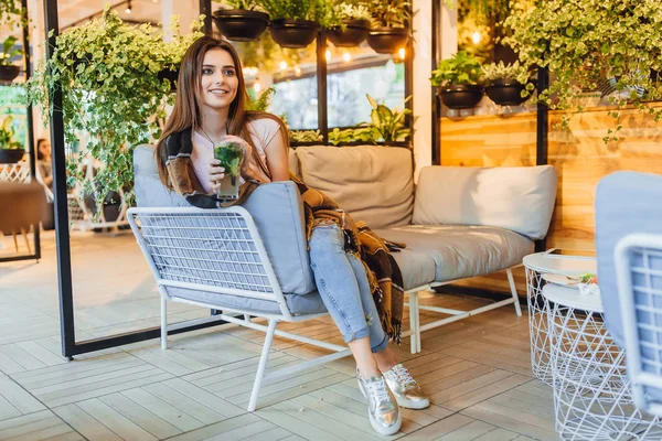 Young woman in casual clothes drinking cocktail on summer terrace