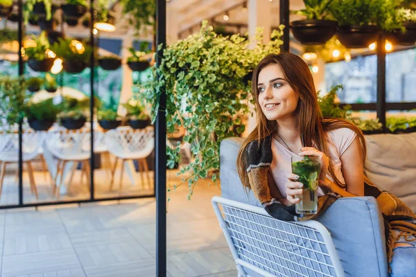 Young woman in casual clothes drinking cocktail on summer terrace