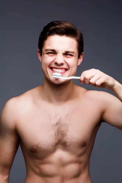 Lächelnder Junger Mann Mit Zahnbürste Zum Zähneputzen Auf Grauem Hintergrund — Stockfoto