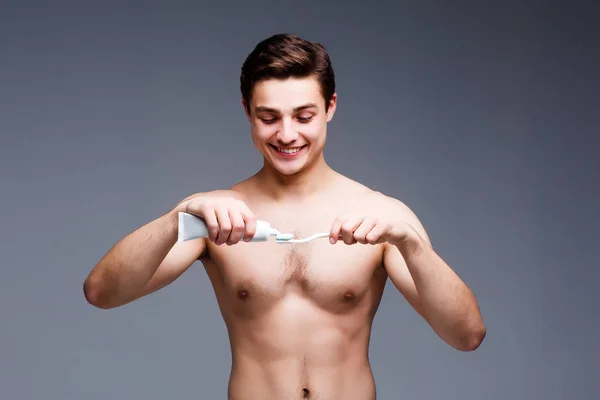 Genç Adam Gri Arka Plan Üzerinde Diş Fırçalama — Stok fotoğraf
