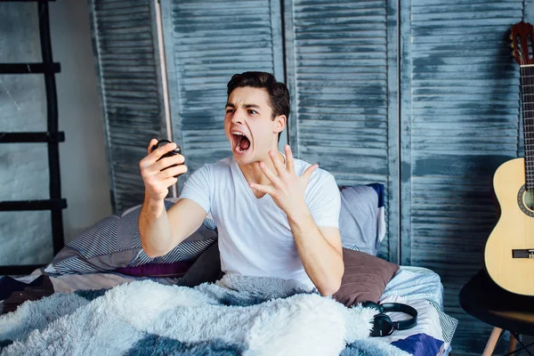 man lying on bed and stopping alarm clock