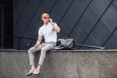 Genç adam güneş gözlüğü ve beyaz gömlek fincan kahve ile dört gözle