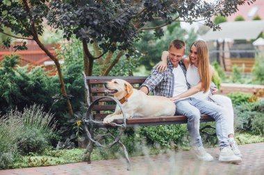 gülümseyen çift tezgah köpekle Park'ta oturuyor.