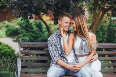 Parkta bankta oturmuş ve gülümseyen genç Çift