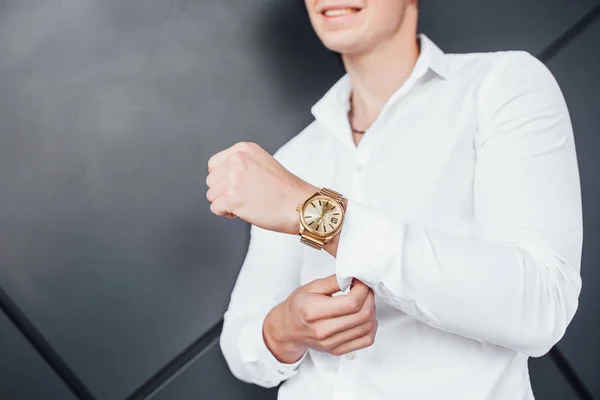 gold watch on hand of businessman in white shirt, cropped view