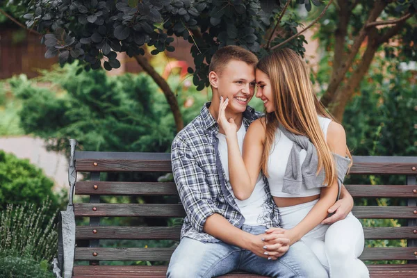 年轻夫妇坐在公园的长凳上 面带微笑 — 图库照片