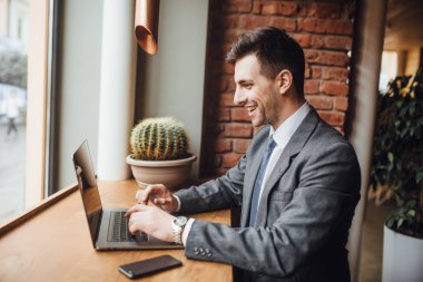 İşadamı pencere yakınındaki kafede otururken, dizüstü arıyorum ve gülümseyen elbiseli