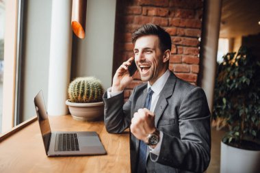 İşadamı modern ofis yakın pencere ve smartphone üzerinde konuşurken oturan takım elbiseli