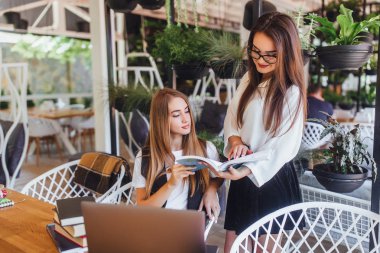 İki güzel kadın yaz teras kitapta bir şey arıyor 