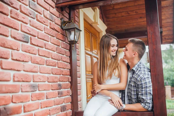 Young family standing at porch of house, hugging and looking at each other
