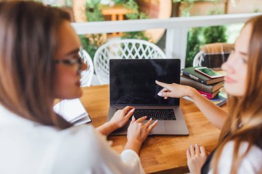 Kafede öğle yemeği zamanı sırasında tartışan iki genç iş kadınları odak üstünde laptop