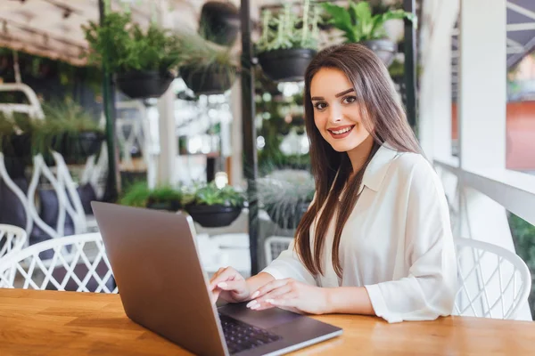 Kafede dizüstü bilgisayar kullanan genç bir kadın, ön plana odaklan