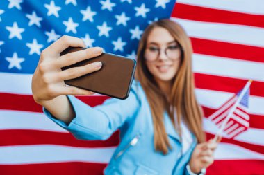 Amerikan bayrağının arka planında selfie çeken genç bir kadın.
