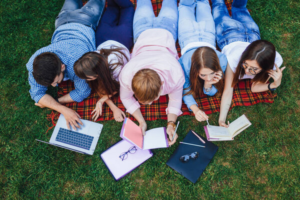 group of young students lying on grass, preparing for lessons