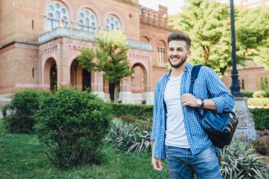 Kampüste durmuş kameraya bakan mavi gömlekli genç adam.