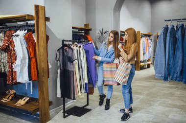 Giysiler seçmek modern moda mağazada alışveriş iki genç kadın 