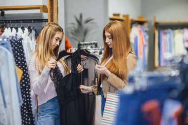 Giysiler seçmek modern moda mağazada alışveriş iki genç kadın 