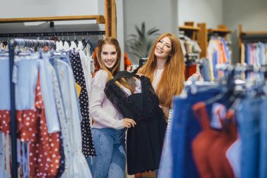 Giysiler seçmek modern moda mağazada alışveriş iki genç kadın 