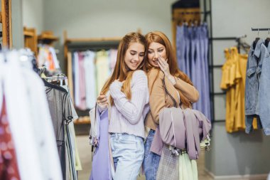 İki genç güzel kadın modern moda mağazada alışveriş