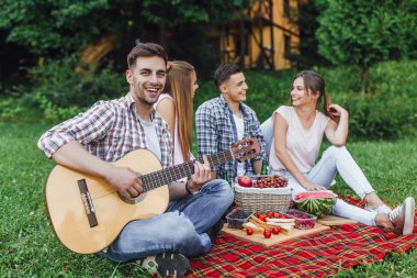 Parkta dört genç çekici arkadaş ve gitar çalan adam