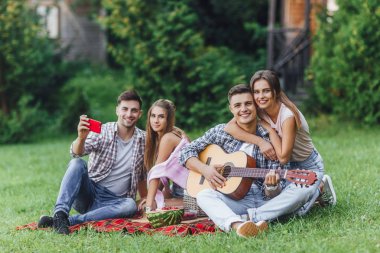 Genç ve çekici dört arkadaş parkta battaniye halısında oturup dinleniyorlar.