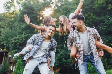 Parkta mutlu çiftler, kadınları omuzlarında taşıyan erkekler 