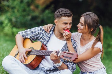 Güzel çift piknik zaman açık zevk, gitar çalmak ve elma yeme