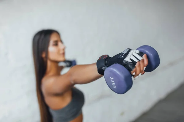 Young beautiful woman exercising with dumbbells on white background