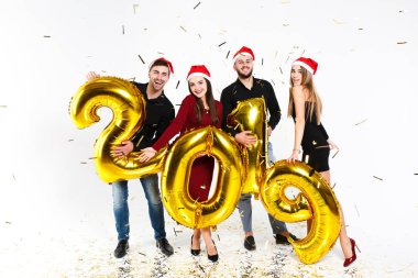 2019'da beyaz arka planda izole edilmiş altın sayılarla balonlarla ayakta duran, yeni yılı kutlayan arkadaş grubunun portresi