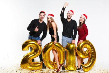 2019'da beyaz arka planda izole edilmiş altın sayılarla balonlarla ayakta duran, yeni yılı kutlayan arkadaş grubunun portresi