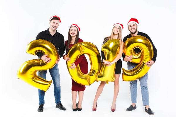 Portrait of group of friends celebrating New Year, standing with balloons with golden numbers in 2019 isolated on white background