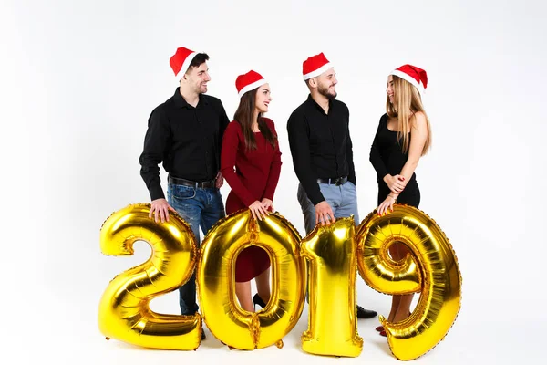 Portrait of group of friends celebrating New Year, standing with balloons with golden numbers in 2019 isolated on white background