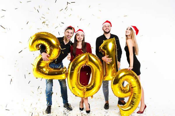 Portrait of group of friends celebrating New Year, standing with balloons with golden numbers in 2019 isolated on white background