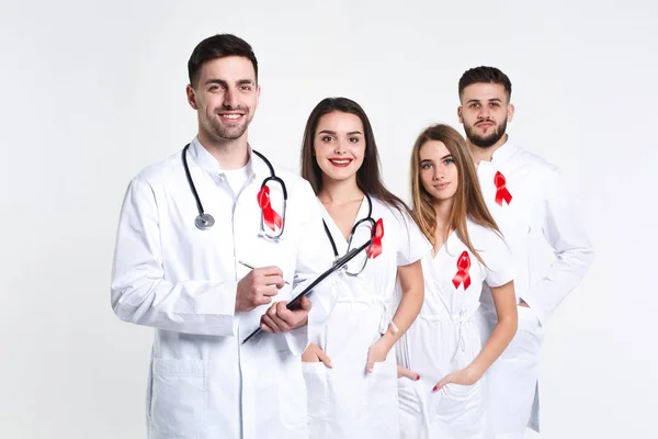 Group of doctors with red ribbons isolated on white background
